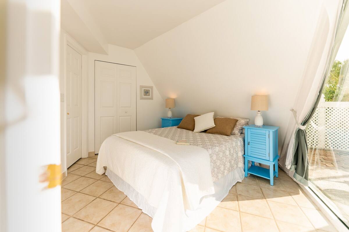 A bedroom with a bed, two nightstands, a door, and a window.