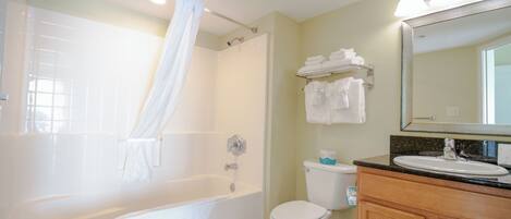 A bathroom with a bathtub, toilet, sink, and vanity.