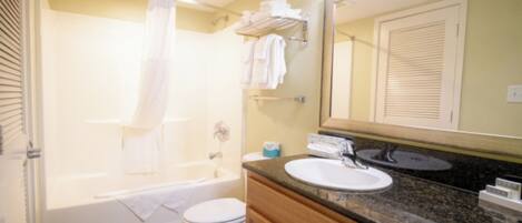 A bathroom with a bathtub, toilet, sink, and a mirror.