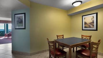 Un coin repas comprenant une table et quatre chaises, un luminaire au plafond et deux tableaux encadrés accrochés aux murs.