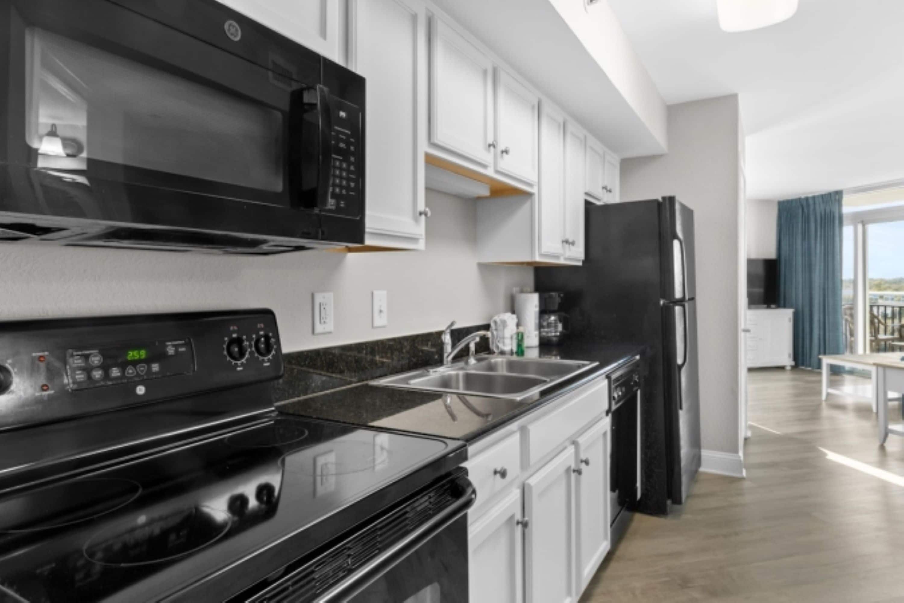 A modern kitchen with a black stove, white cabinets, and a black refrigerator.