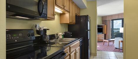 A kitchen with a black stove, wooden cabinets, and a black refrigerator.