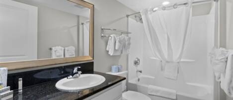 Un baño moderno con lavamanos, espejo y bañera blancos.