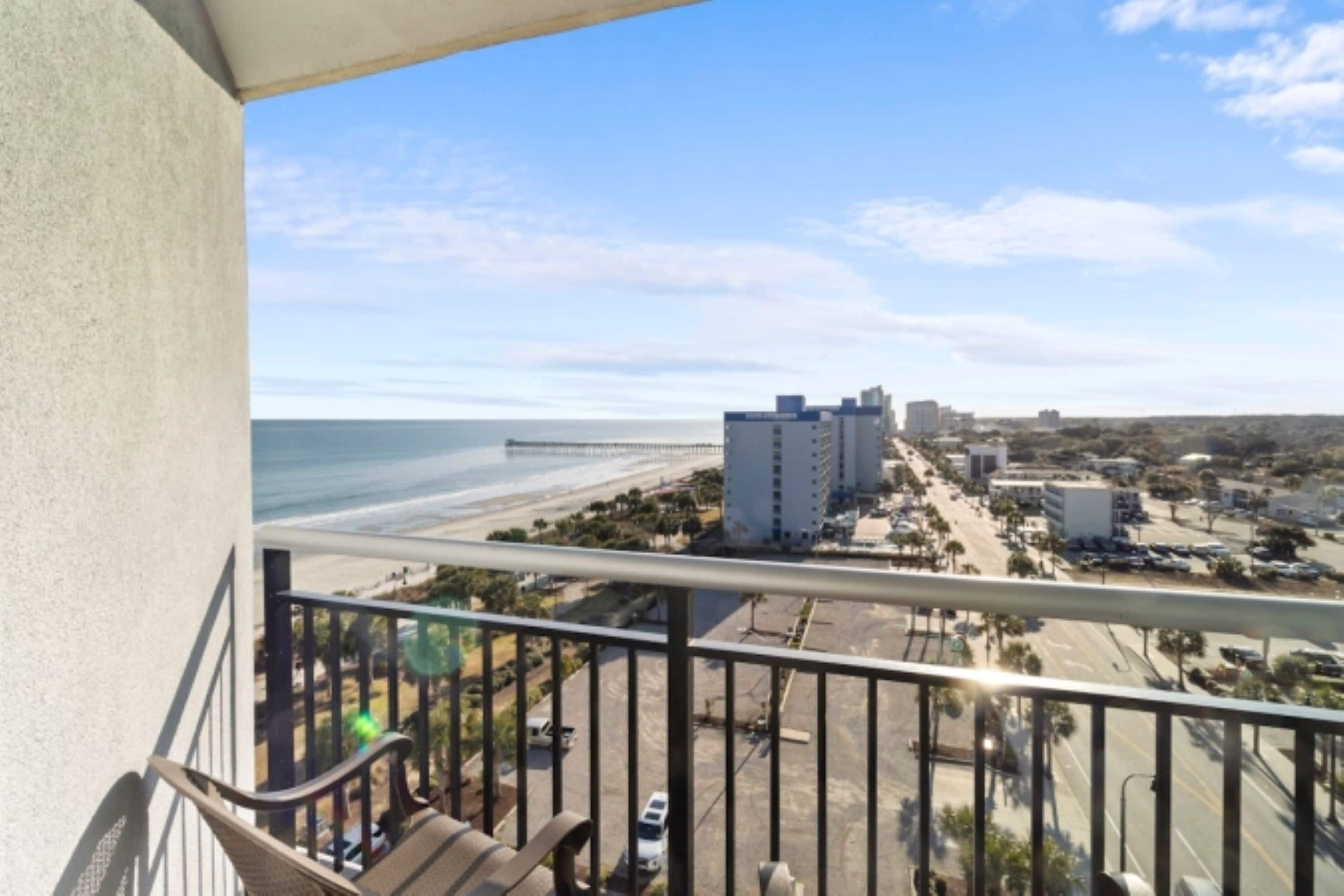 A balcony with a view of a beach and buildings.