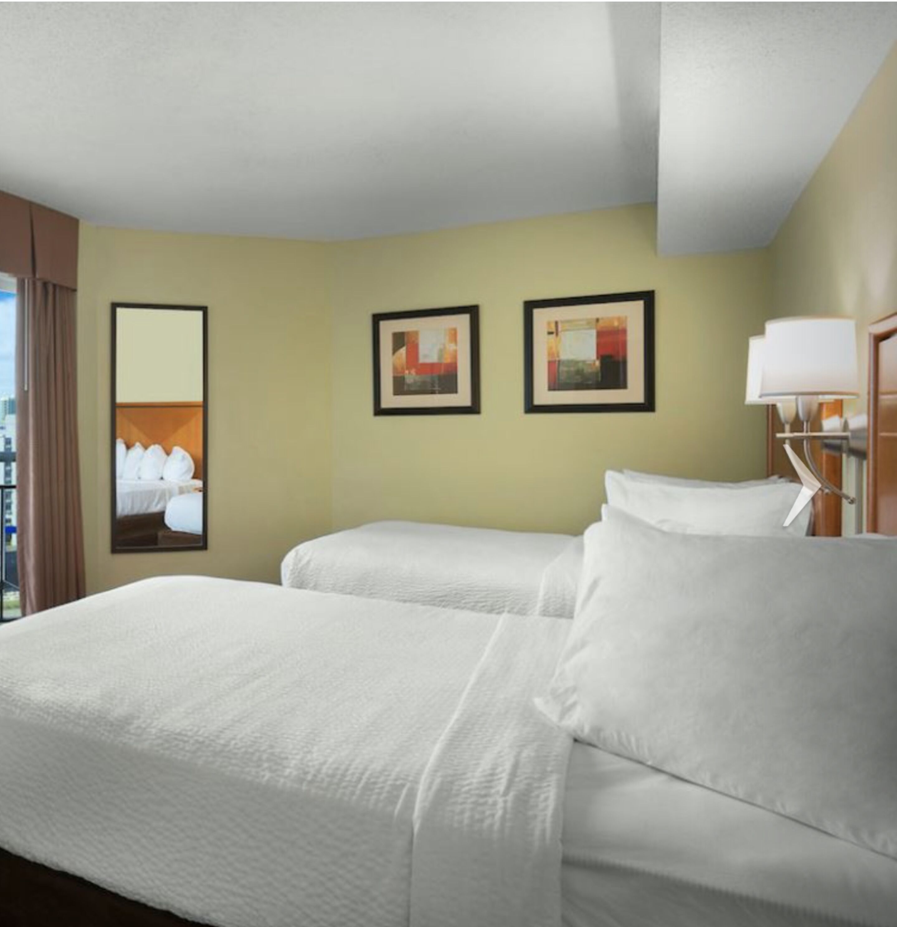 Habitación de hotel con dos camas, un ventanal grande y obras de arte en las paredes.