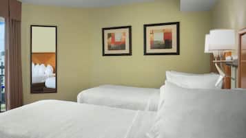 Habitación de hotel con dos camas, un ventanal grande y obras de arte en las paredes.