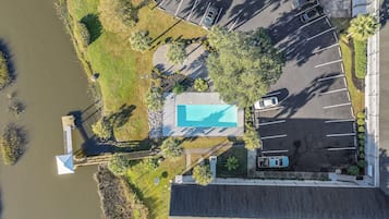 Vue aérienne d’une propriété dotée d’une piscine, d’un parking et d’une jetée s’étendant dans une étendue d’eau.