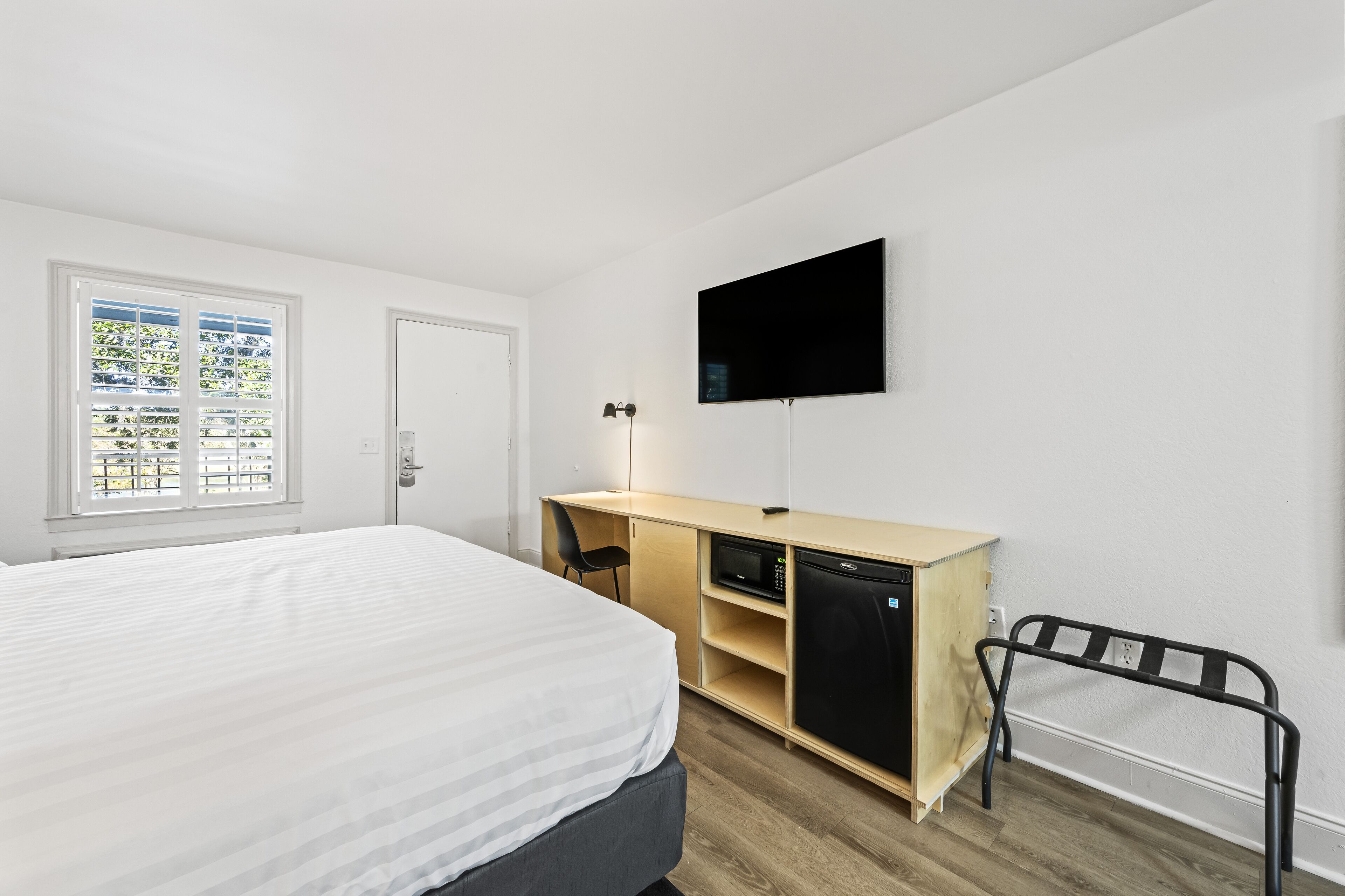 Un dormitorio con cama, escritorio, televisor y armario.