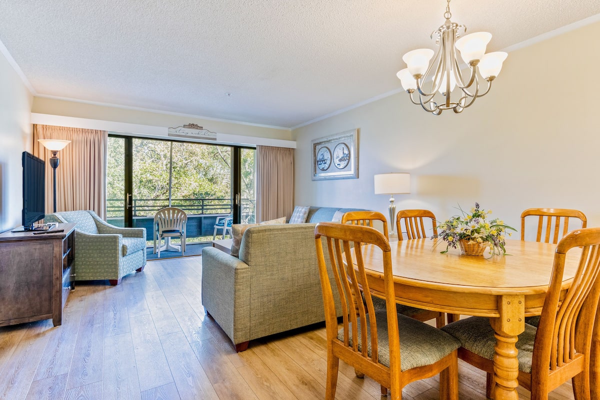 A spacious room with a dining table, chairs, a sofa, and a television.