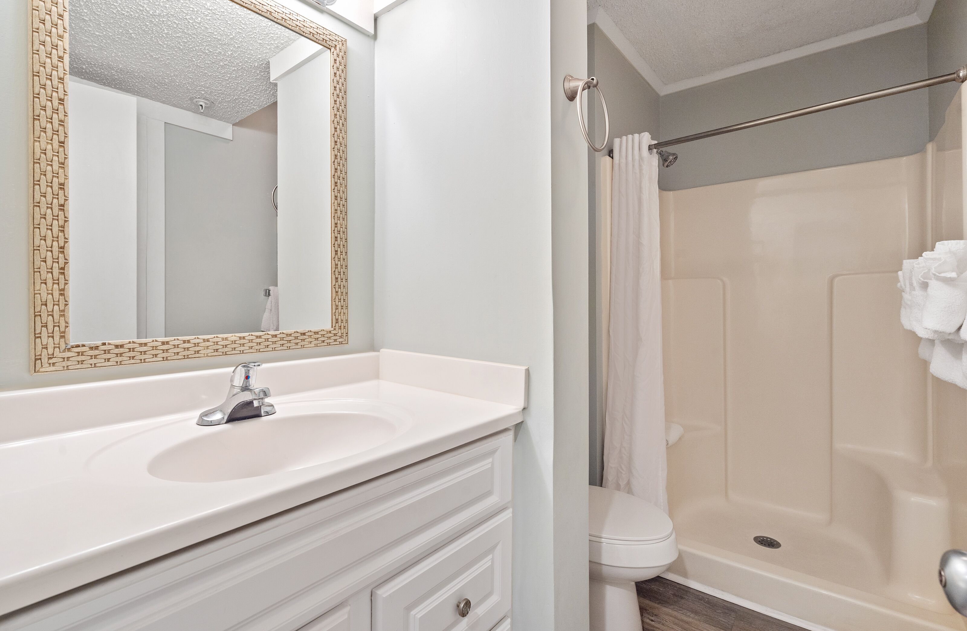 Une salle de bain avec un lavabo blanc, un miroir et un rideau de douche.
