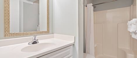 A bathroom with a white sink, mirror, and shower curtain.