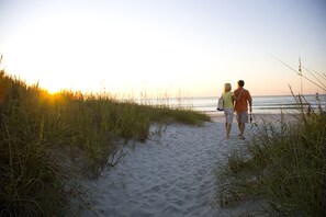 A pathway leading to the beach with sand and grass on either side. - Ocean Creek Resort (Myrtle Beach)