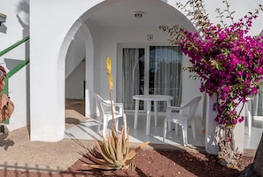 Un bâtiment blanc doté d’un balcon, d’une petite table et de chaises.