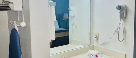 A bathroom with a sink, mirror, and hairdryer.