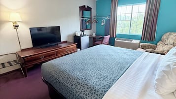 Une chambre d’hôtel équipée d’un lit, d’une télévision, d’un bureau, d’une chaise, d’un miroir et d’une fenêtre.