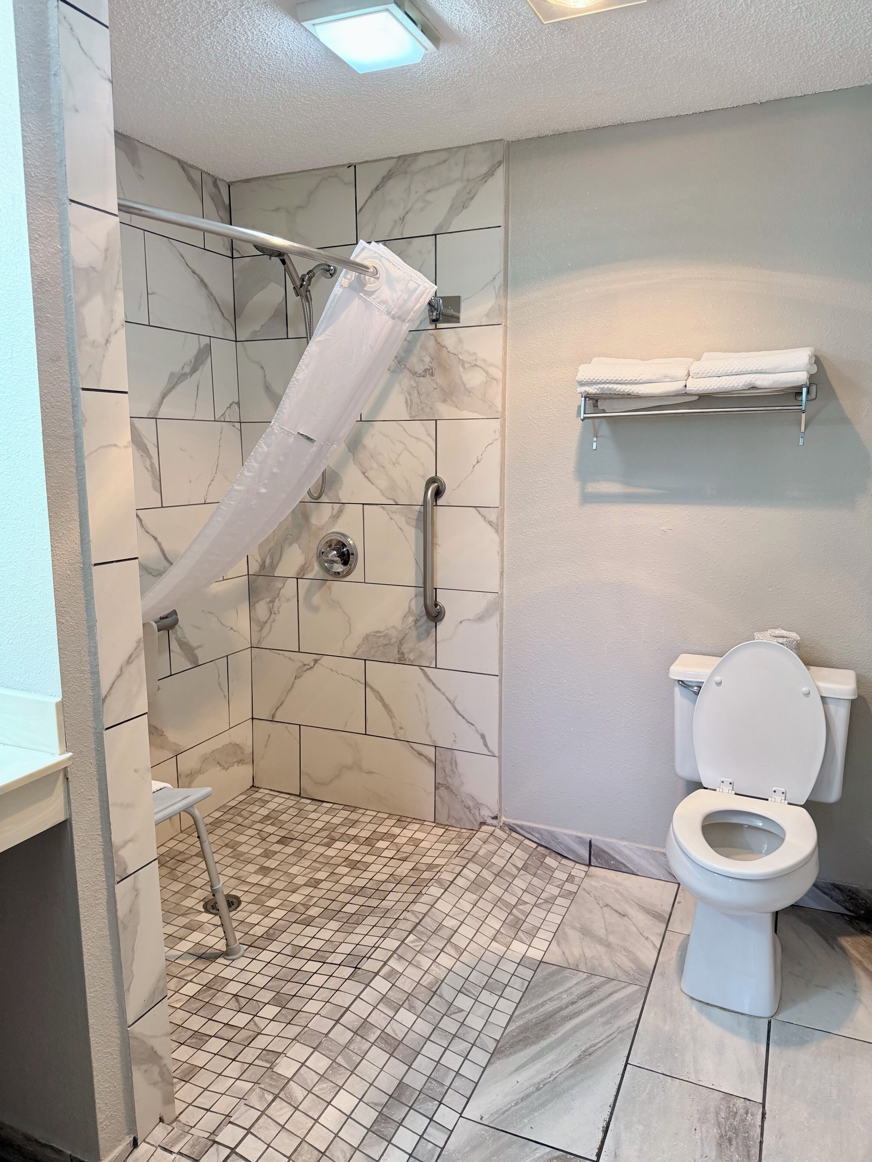Ein Badezimmer mit Dusche, Toilette und Handtuchhalter.