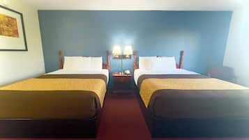 Quarto de hotel com duas camas, uma mesinha de cabeceira com luminárias e um quadro na parede.