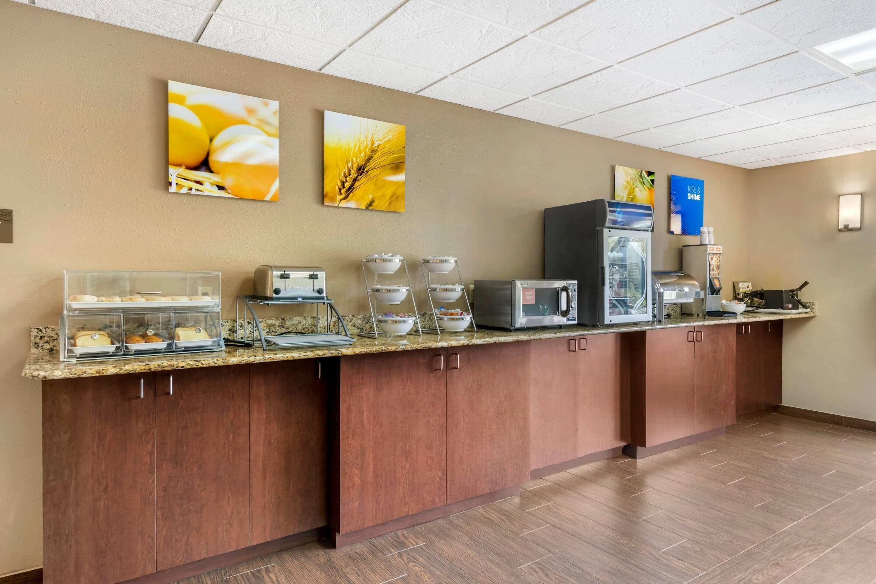 Un comedor de hotel con mostrador, máquinas de café y un refrigerador.