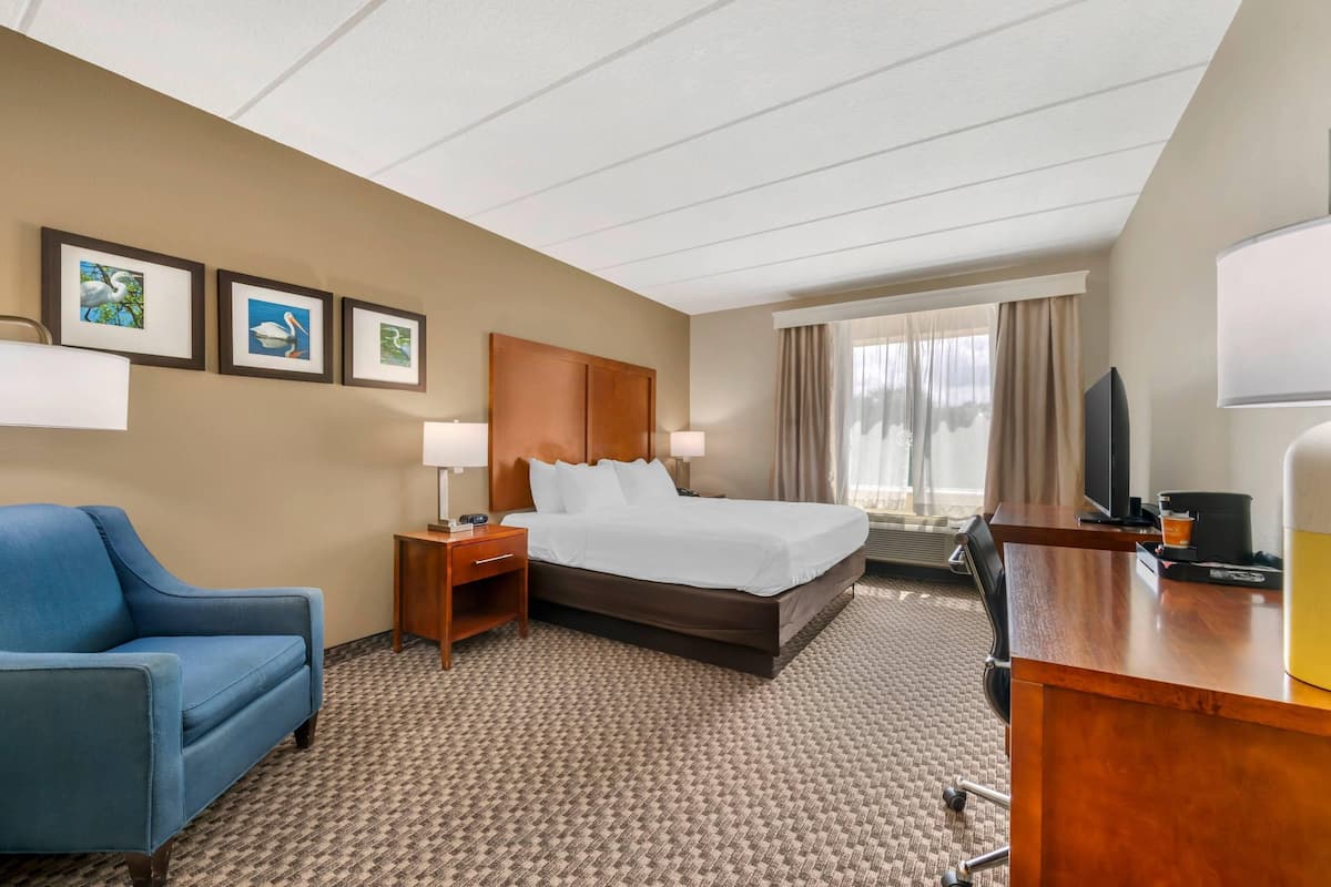 Ein Hotelzimmer mit Bett, Schreibtisch, Stuhl und gerahmten Bildern an der Wand.