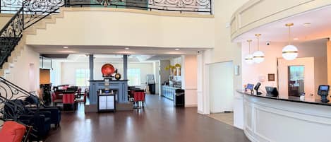 Tilava aula, jossa on suuri portaikko, vastaanottotiski ja koristeellinen kattokruunu.