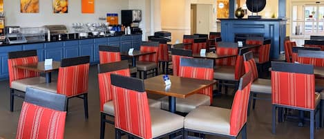 Un ristorante con diversi tavoli e sedie, un bancone con attrezzature da cucina e un pilastro blu.