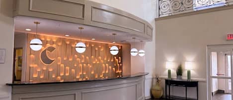 A reception area with a curved counter, pendant lighting, and a decorative wall panel.