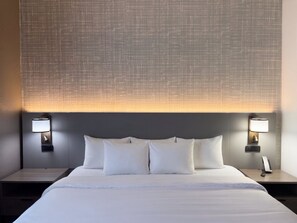 A hotel room with a large bed, two bedside tables, and wall-mounted lamps. - Comfort Suites Galveston Cruise Port Area – Beachside (Galveston)