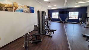 A gym with exercise equipment, a treadmill, and a mirror wall.