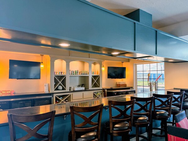 A bar area with a counter, seating, and a television. - Comfort Suites Galveston Cruise Port Area – Beachside (Galveston)