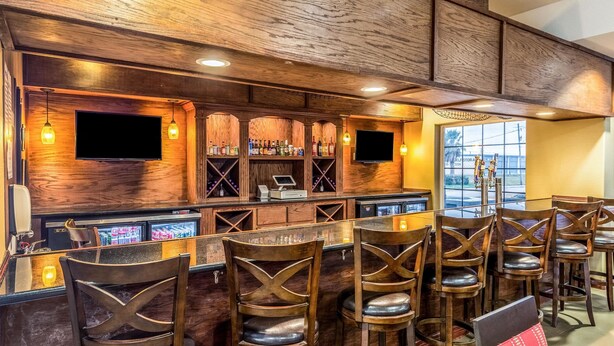 A bar area with wooden decor, a TV, and a seating arrangement. - Comfort Suites Galveston Cruise Port Area – Beachside (Galveston)