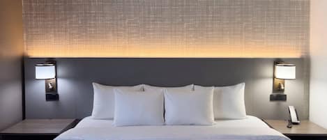 Ein Hotelzimmer mit einem großen Bett, zwei Nachttischen und einem Kopfteil mit einer strukturierten Musterung.