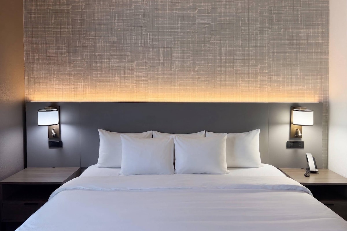 Ein Hotelzimmer mit einem großen Bett, zwei Nachttischen und einer Wandlampe.