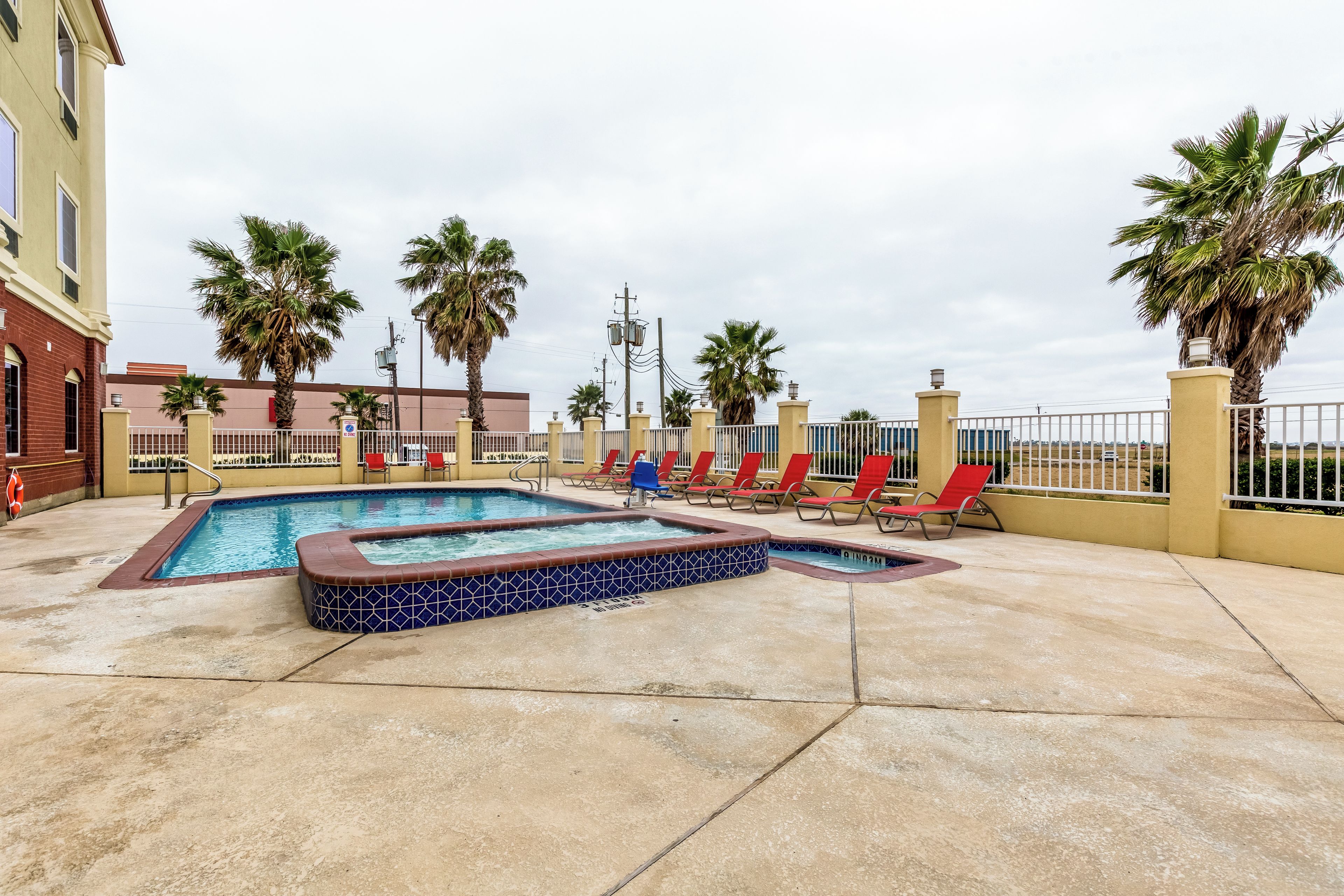 A pool area with multiple pools, lounge chairs, and palm trees.