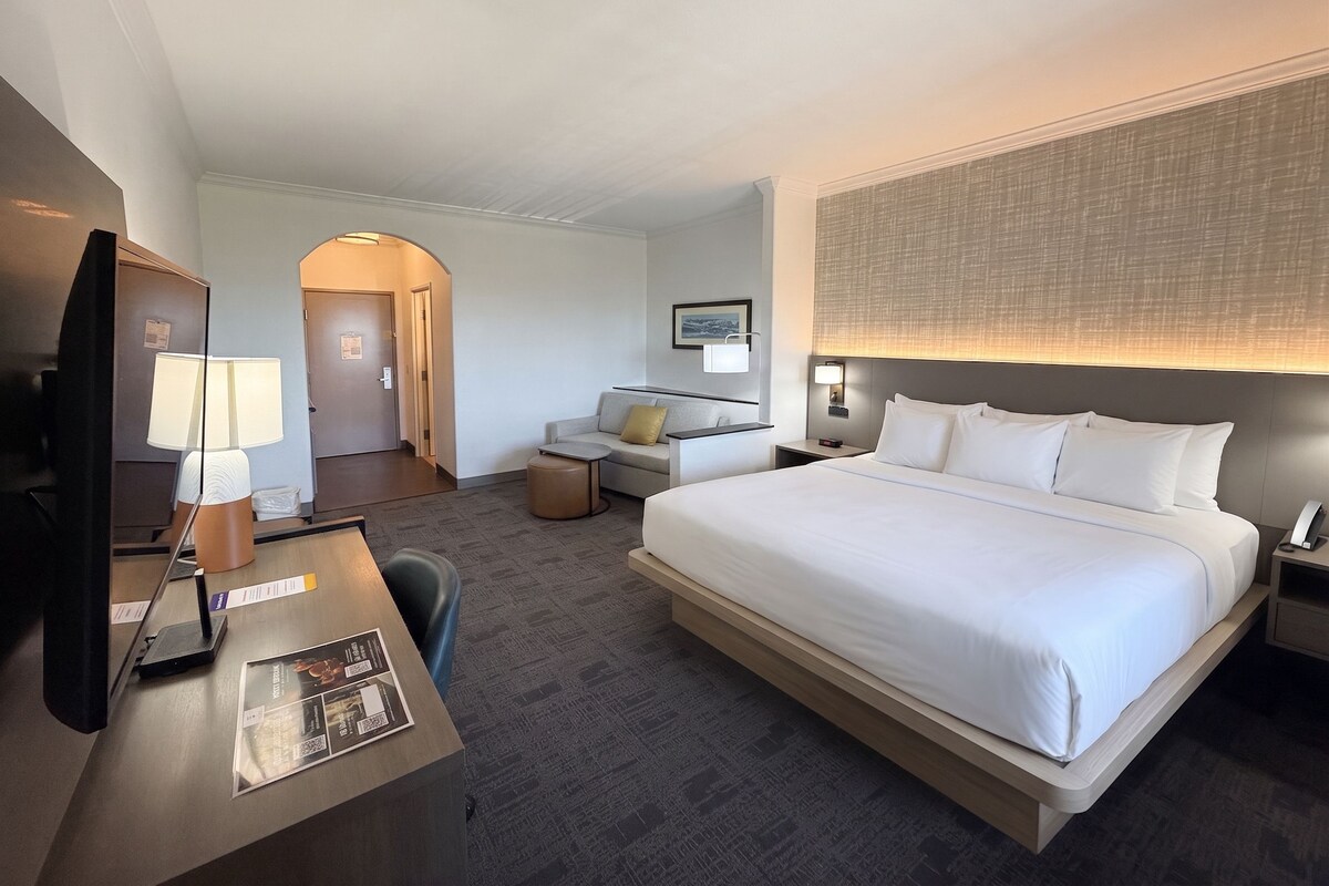 Una habitación de hotel con cama, escritorio, silla y televisor.