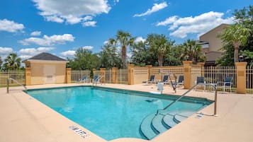 Una piscina al aire libre, sillones reclinables de piscina