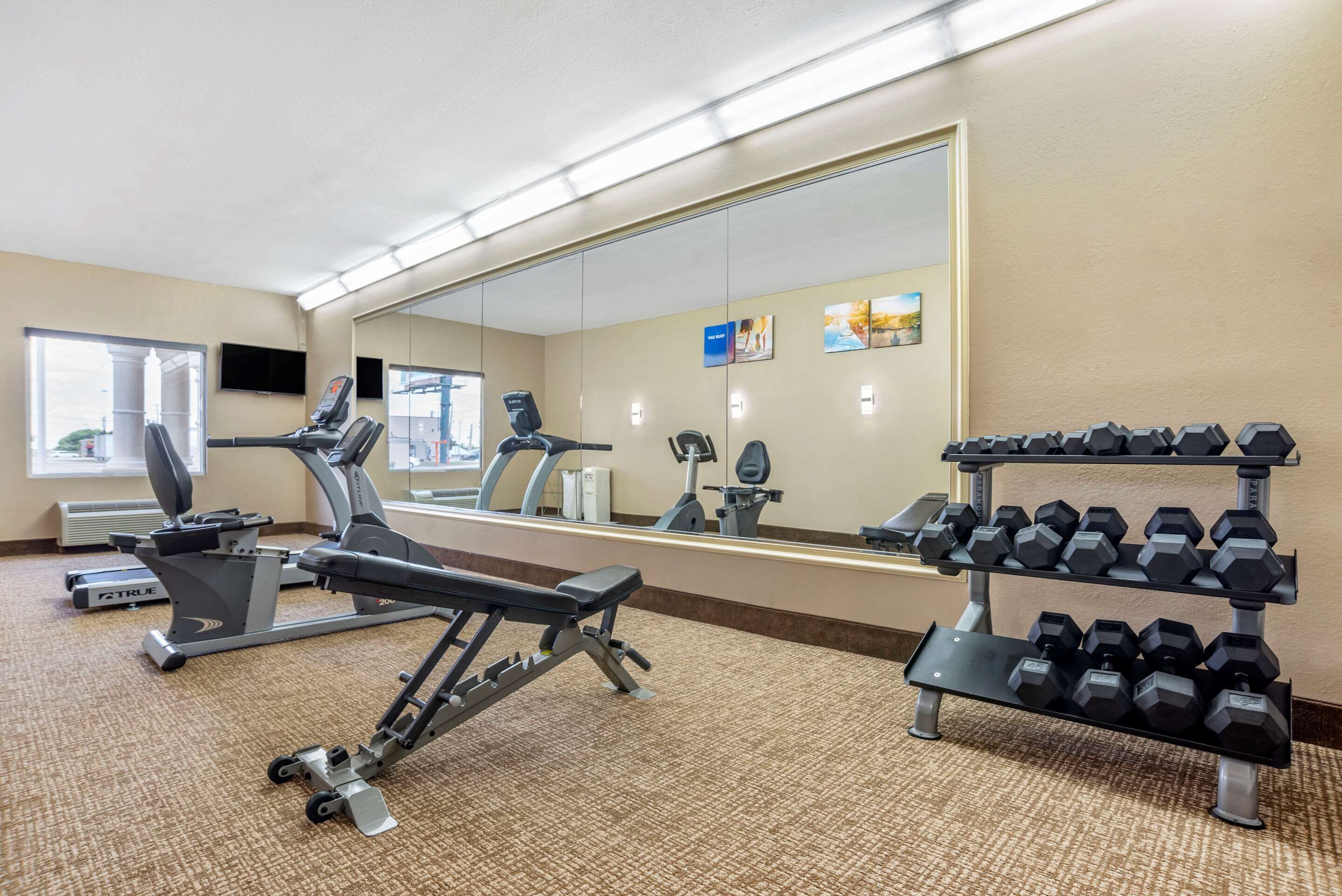 A gym with exercise equipment, a mirror, and a dumbbell rack.