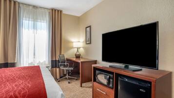Une chambre d’hôtel équipée d’un lit, d’un bureau, d’une télévision, d’un four à micro-ondes et d’un réfrigérateur.
