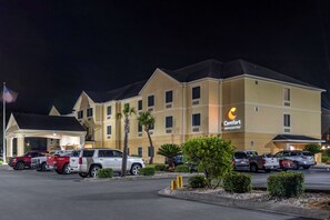 Un hotel Comfort Inn & Suites con un estacionamiento y varios SUVs estacionados al frente.