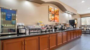 Un bufé de desayuno con diferentes opciones de comida, un refrigerador y un televisor.