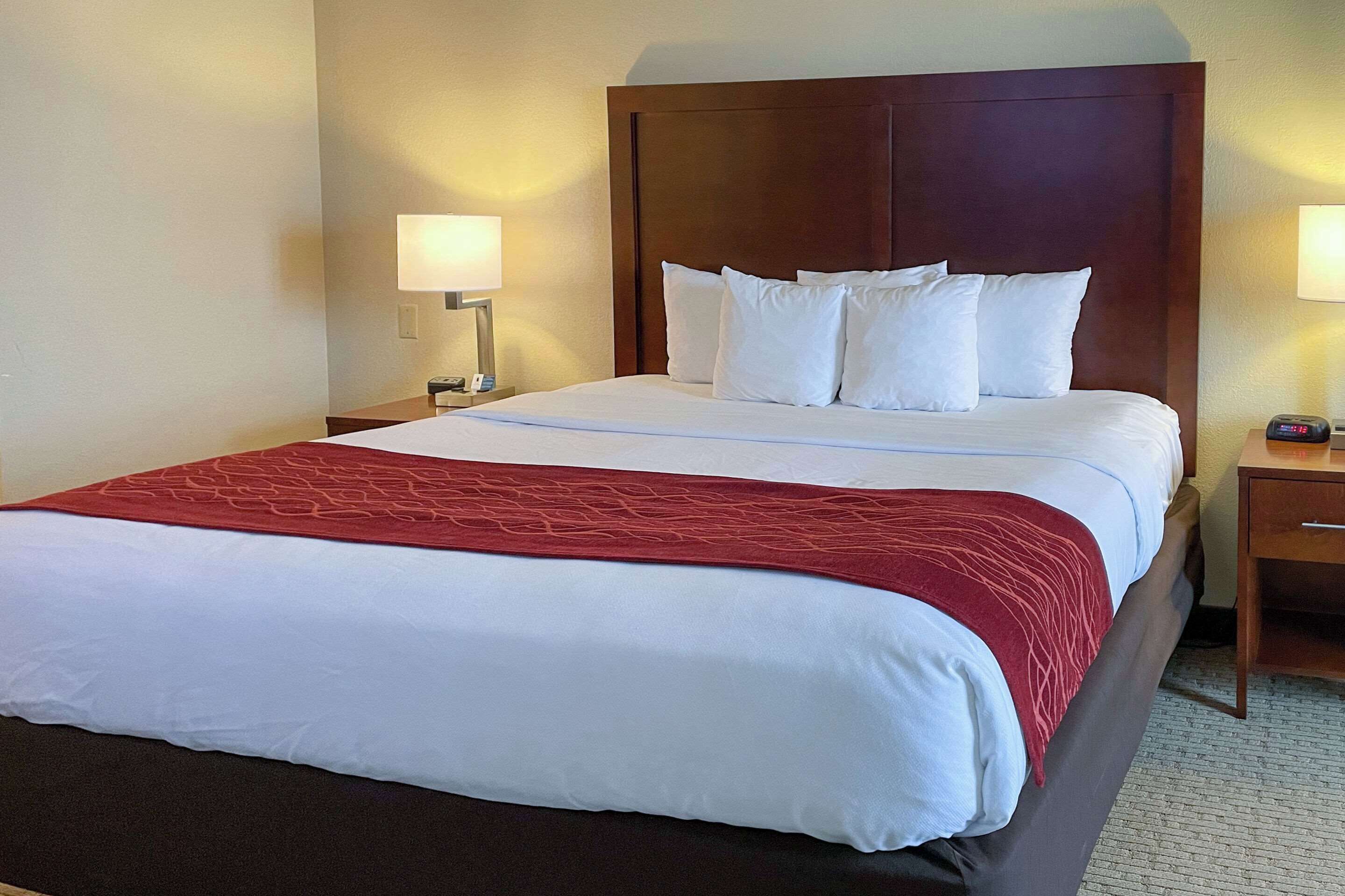 A hotel room with a large bed, two bedside tables, and a wooden headboard.