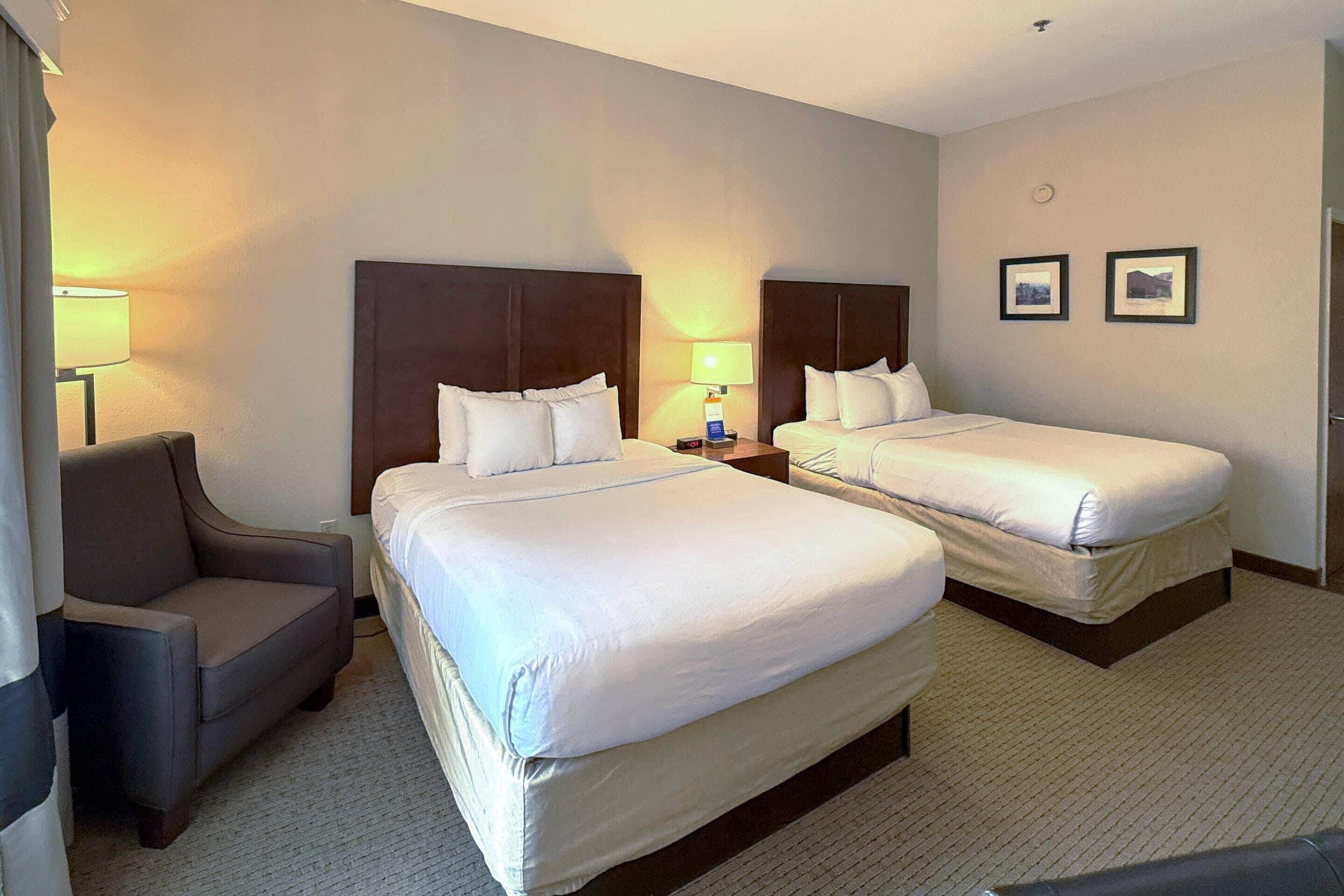 A hotel room with two single beds, a sofa, and a desk.