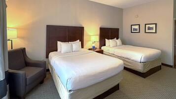A hotel room with two single beds, a sofa, and a desk.