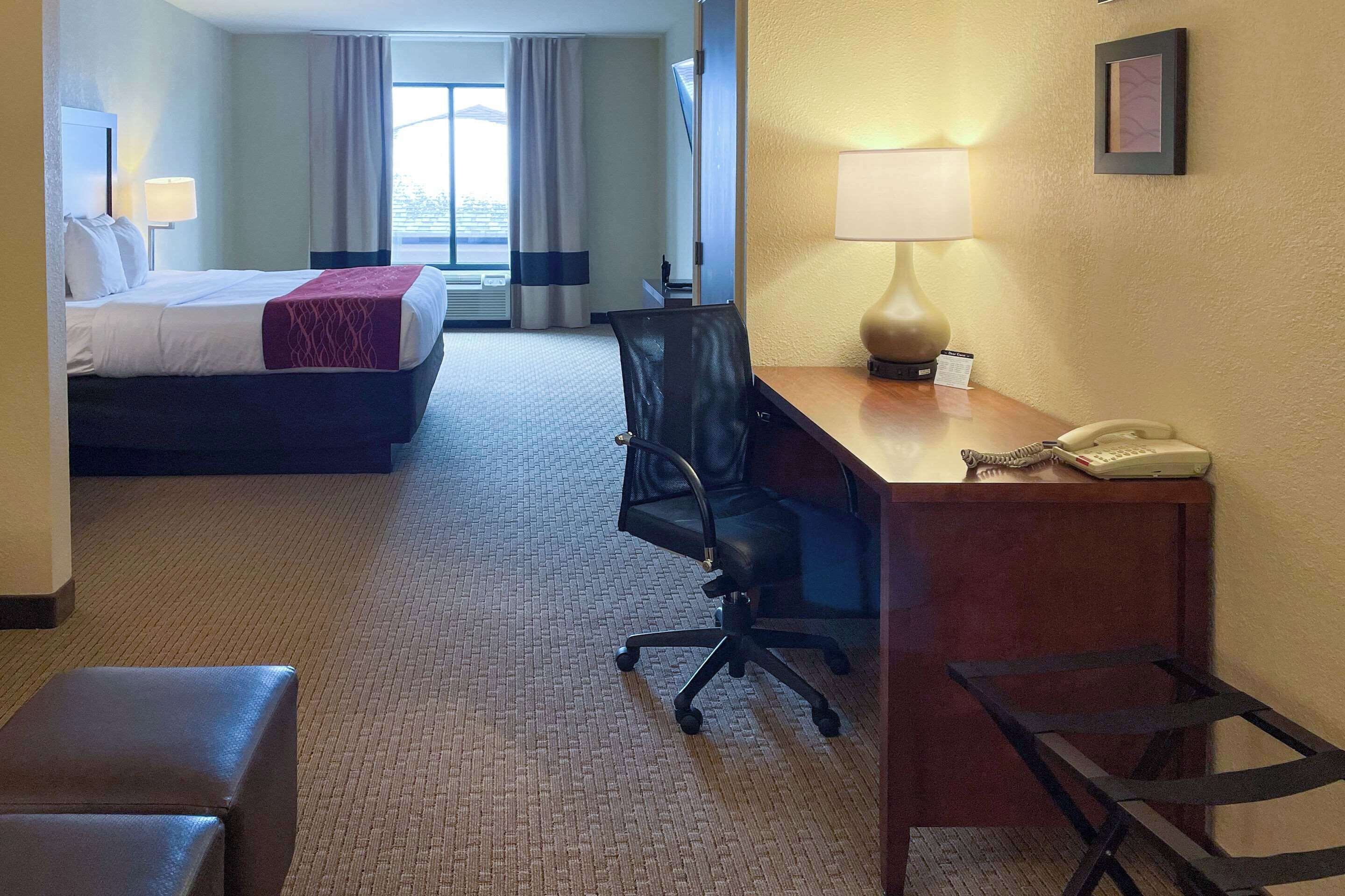 A hotel room with a bed, desk, chair, and a telephone.