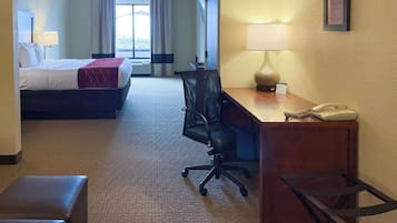 A hotel room with a bed, desk, chair, and a telephone.