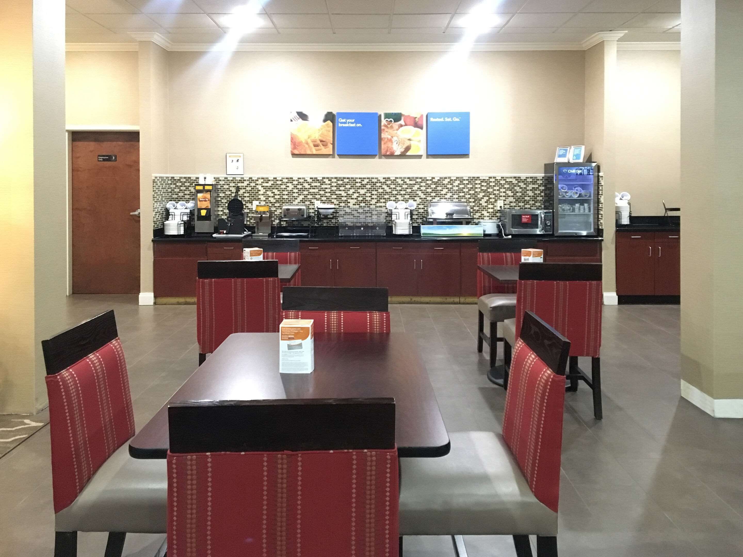 A restaurant with booths and a counter, a tiled backsplash, and a menu board above the counter.