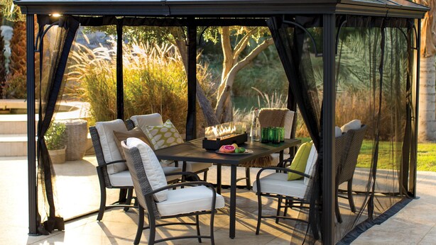 A gazebo with a table and chairs, surrounded by greenery.