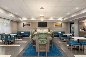 Un comedor moderno con una mesa central, sillas tapizadas en azul y una alfombra azul.