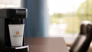 A Hamilton Beach commercial coffee maker with a disposable cup labeled "La Quinta" on a table.