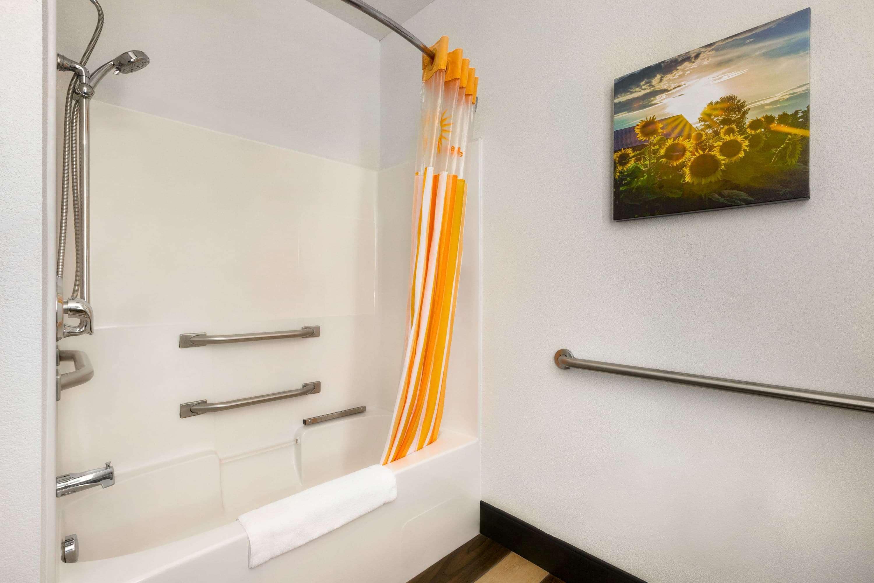 A bathroom with a shower, grab bars, and a towel rack.