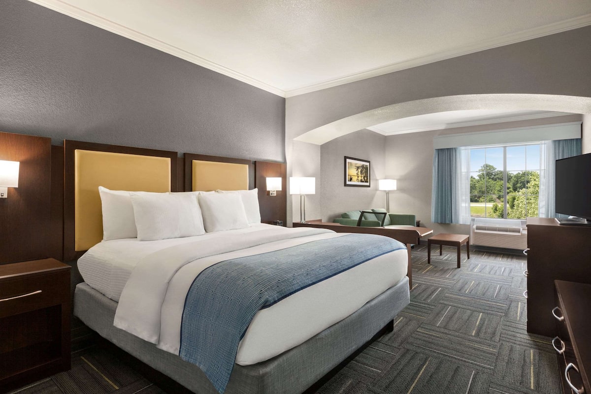 A hotel room with a large bed, a desk, a chair, and a television.